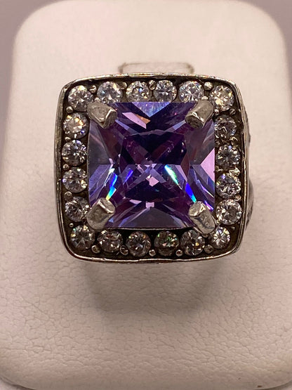 Solitario de plata .925 con zirconia morada, halo y banda pavimentada sobre fondo neutro — joyería artesanal Taxco