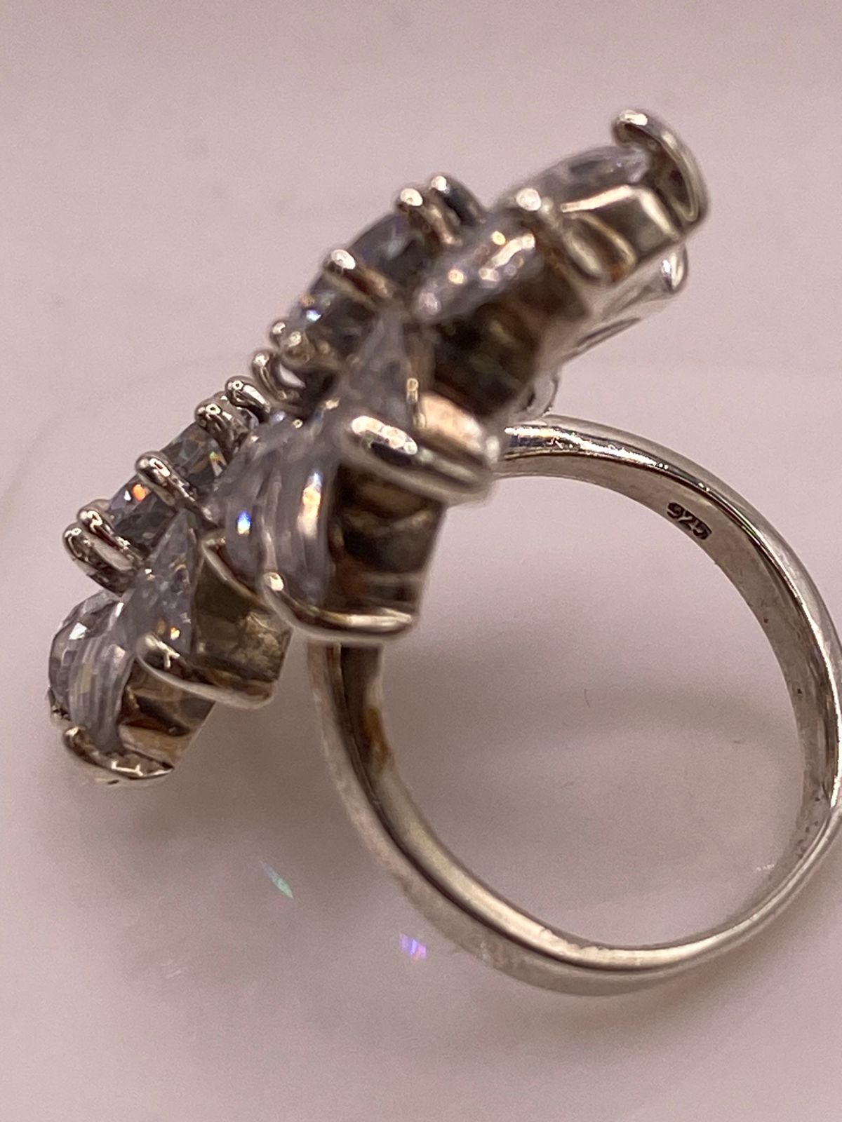 Close-up de zirconias transparentes engastadas en anillo floral artesanal de plata 925