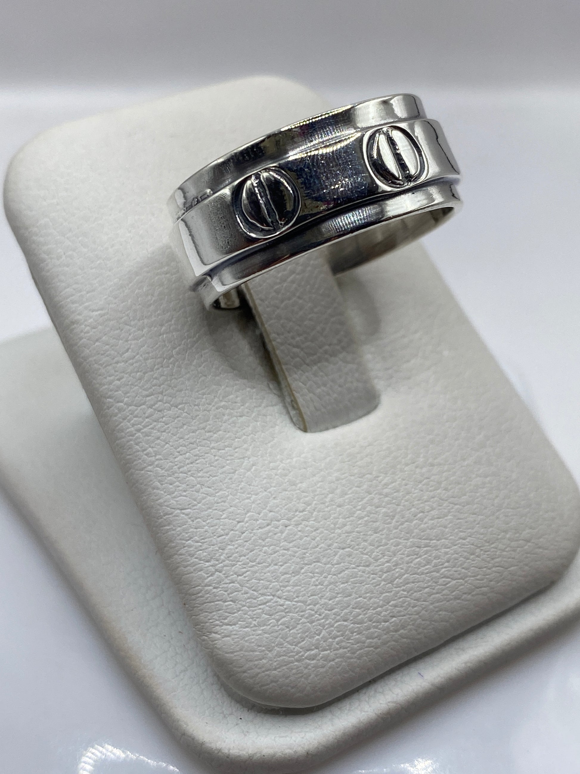 Anillo de plata en la mano de un hombre mostrando el acabado pulido y la densidad del metal