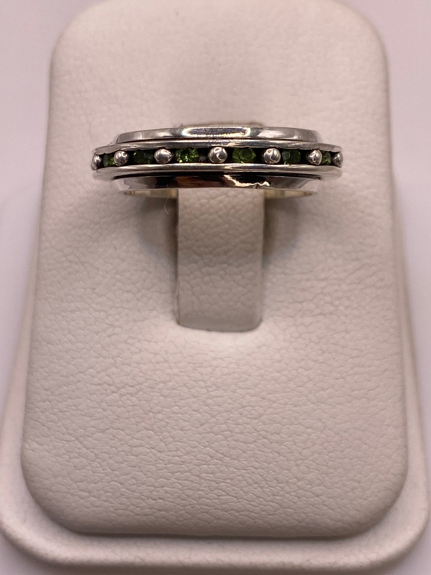 Anillo giratorio de plata .925 con circonias blancas y verdes en el dedo de una mujer