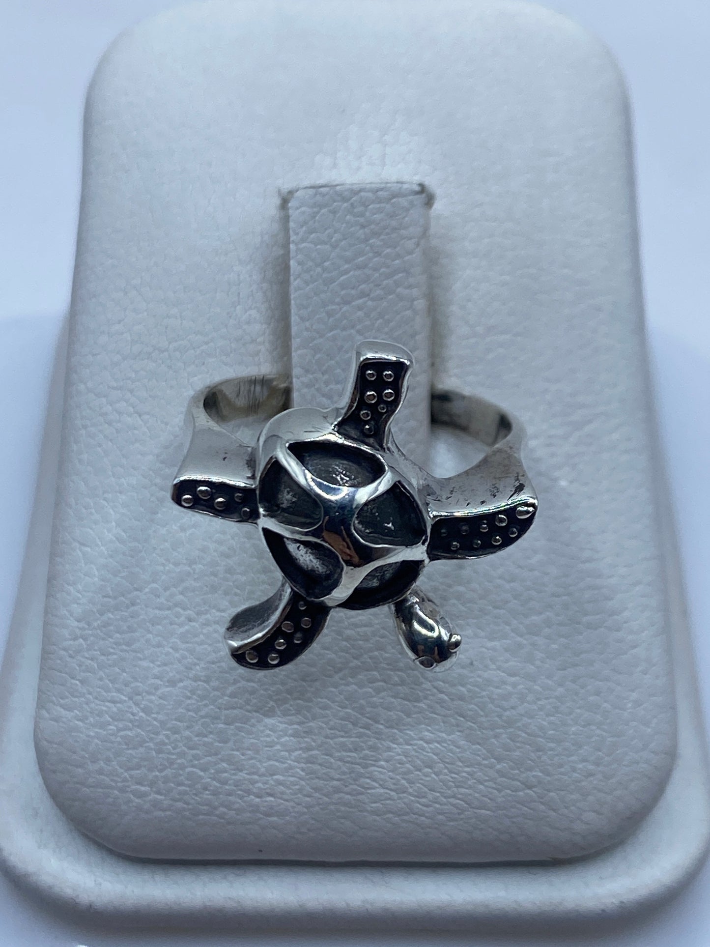 Anillo de plata .950 con diseño de tortuga artesanal, visto de frente sobre mano de mujer