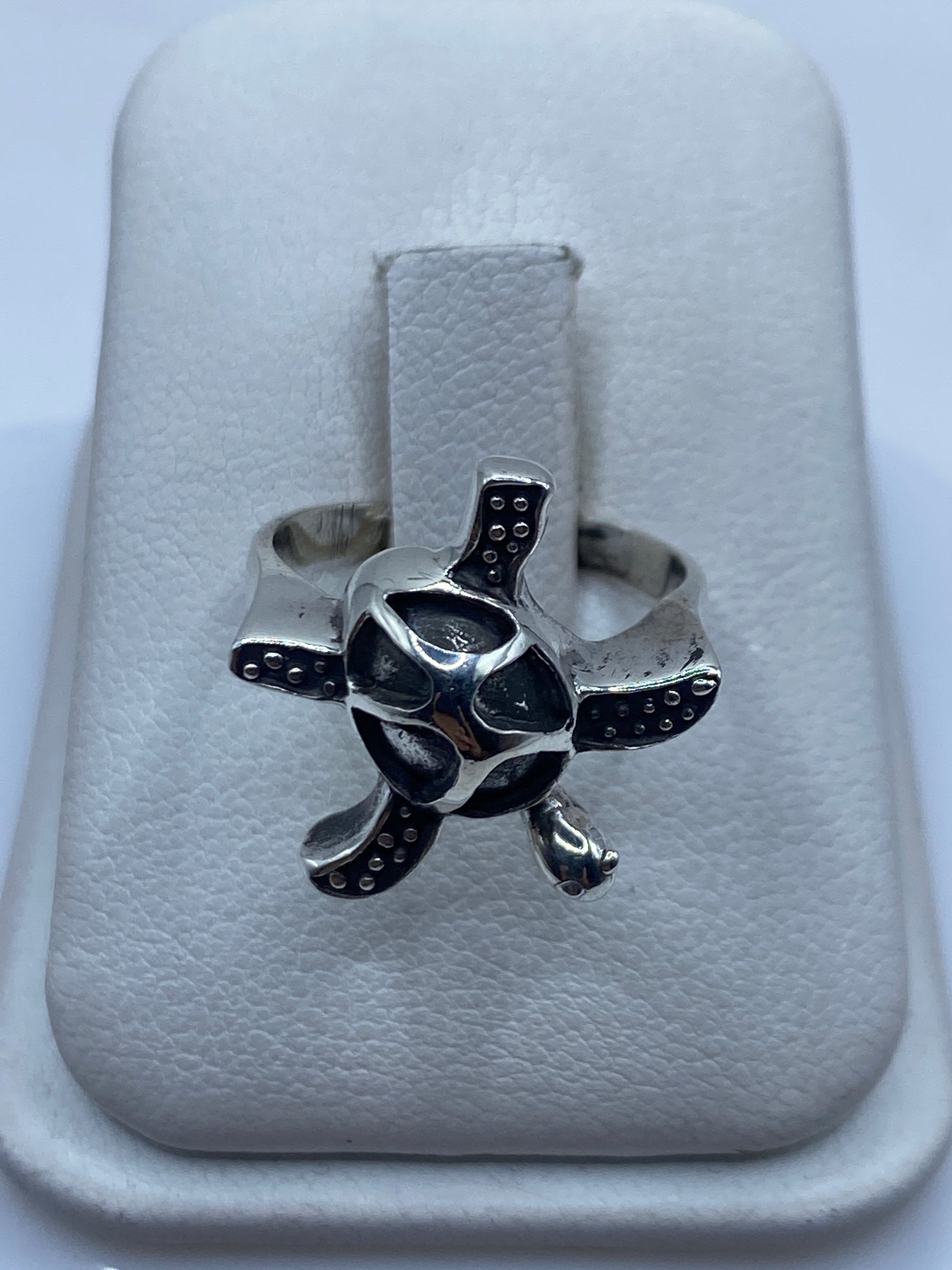 Anillo de plata .950 con diseño de tortuga artesanal, visto de frente sobre mano de mujer