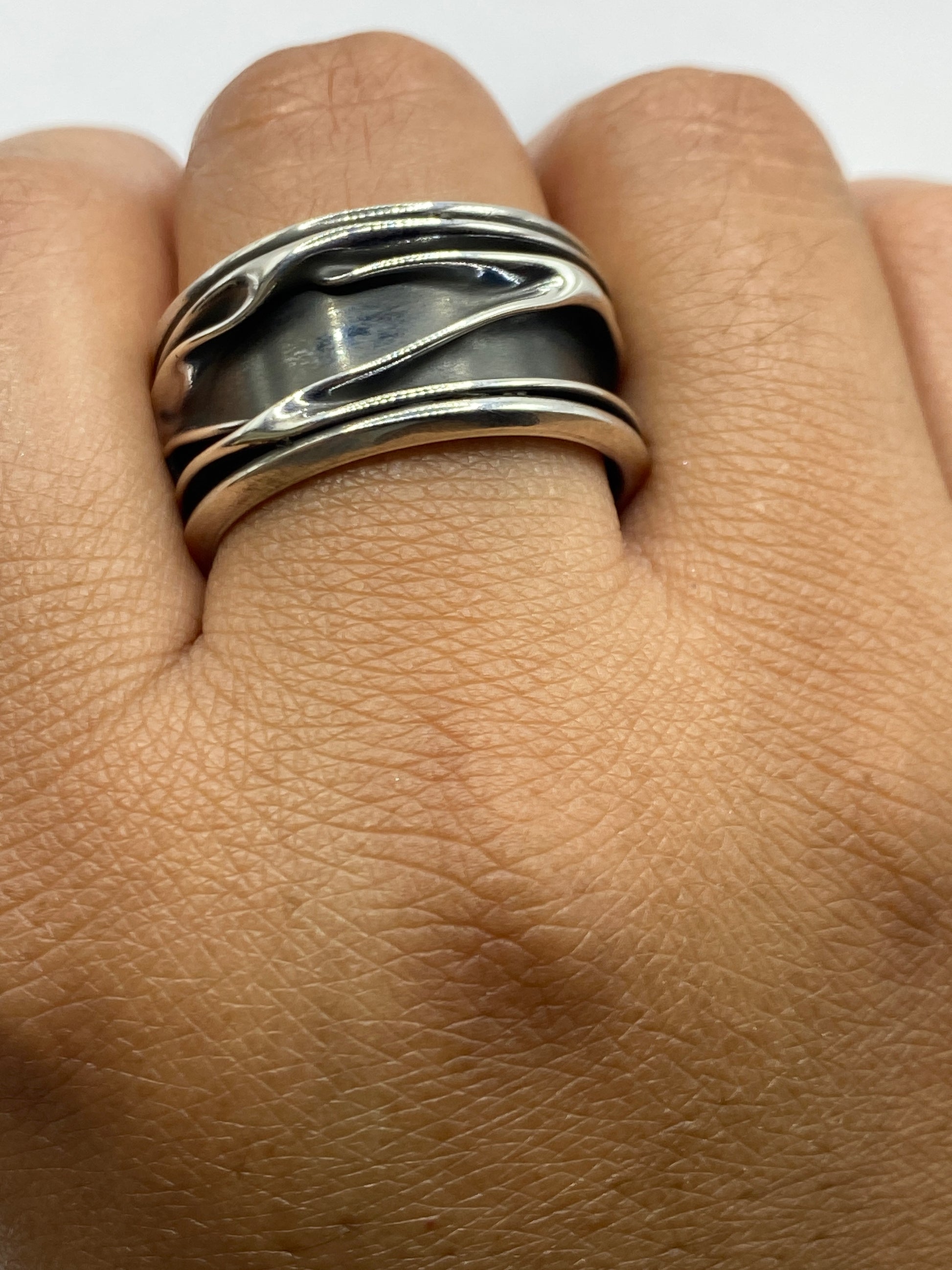 Anillo completo de plata con bandas superpuestas sobre fondo blanco, vista de frente