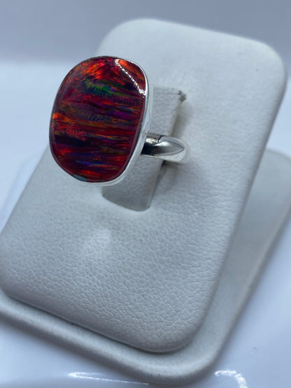 Detalle del ópalo de fuego en anillo ajustable mostrando juego de colores naranja, rojo y verde