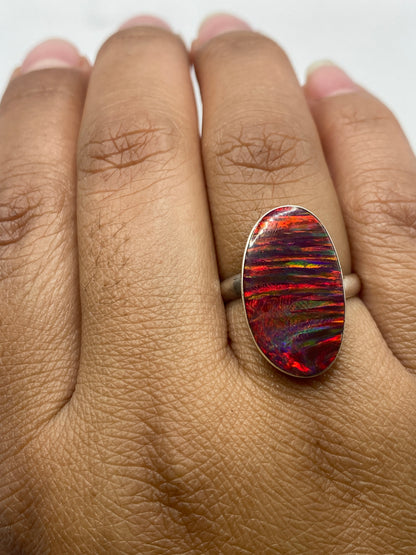 Anillo ajustable de plata .950 con ópalo de fuego en fondo neutro mostrando sello de ley