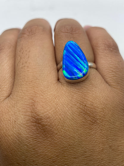 Anillo ajustable con sello 950 y ópalo azul sobre fondo oscuro