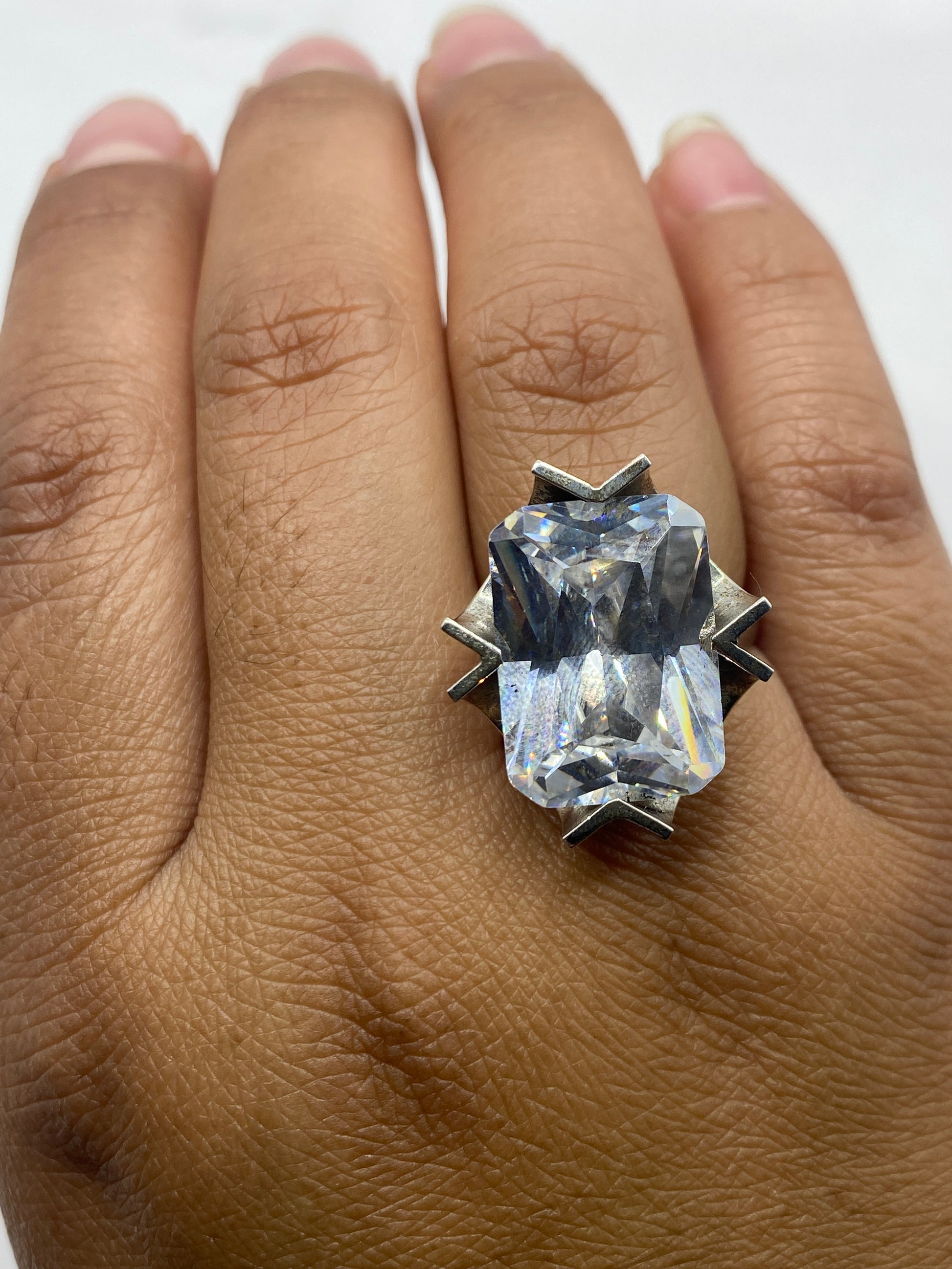 Anillo solitario brillante sobre base gris mostrando el fuego de la piedra