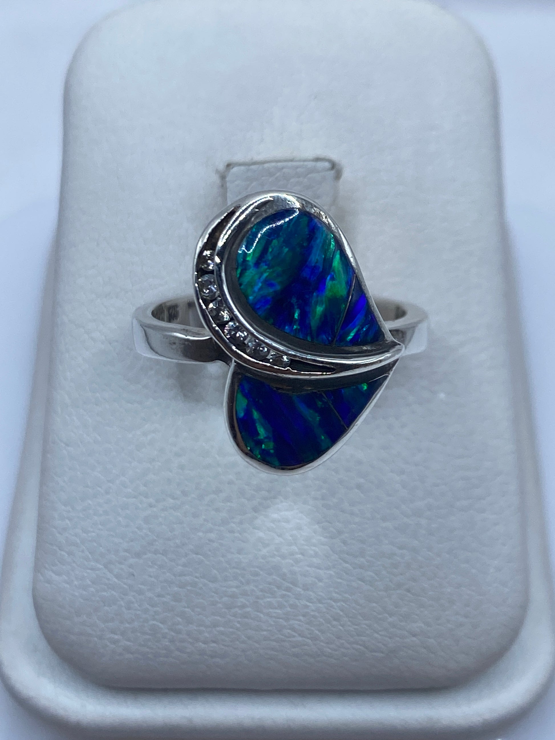 Anillo de plata con ópalo de fuego azul en la mano de una mujer, mostrando juego de colores
