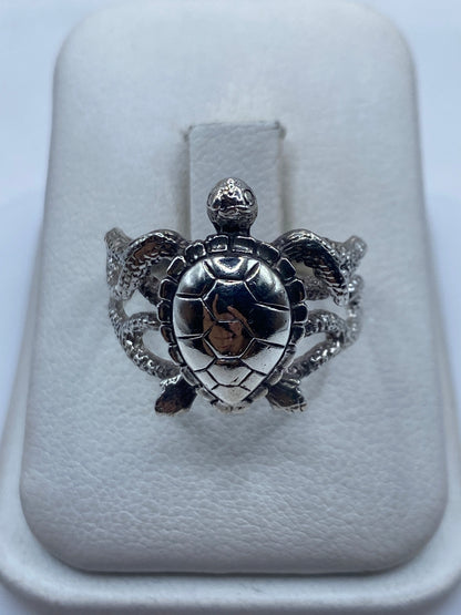 Anillo de plata .950 con dos tortugas en relieve sobre fondo blanco