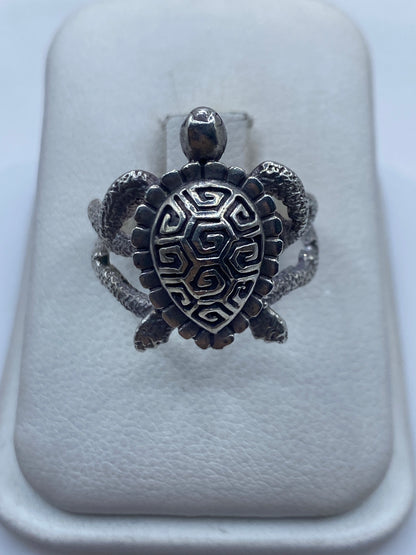 Anillo tortuga prehispánico en plata .950, caparazón geométrico con espiral grabada, sobre dedo de mujer
