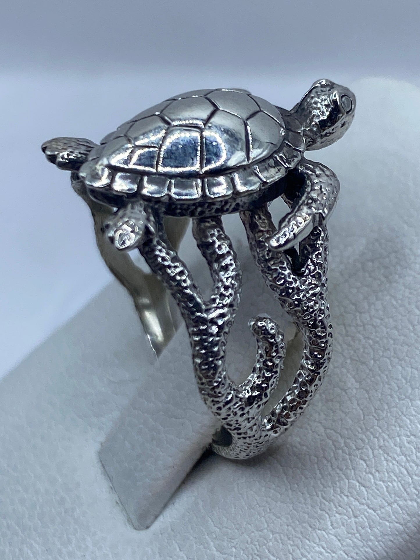 Anillo de plata .950 en la mano de una mujer, con relieve artesanal de tortuga