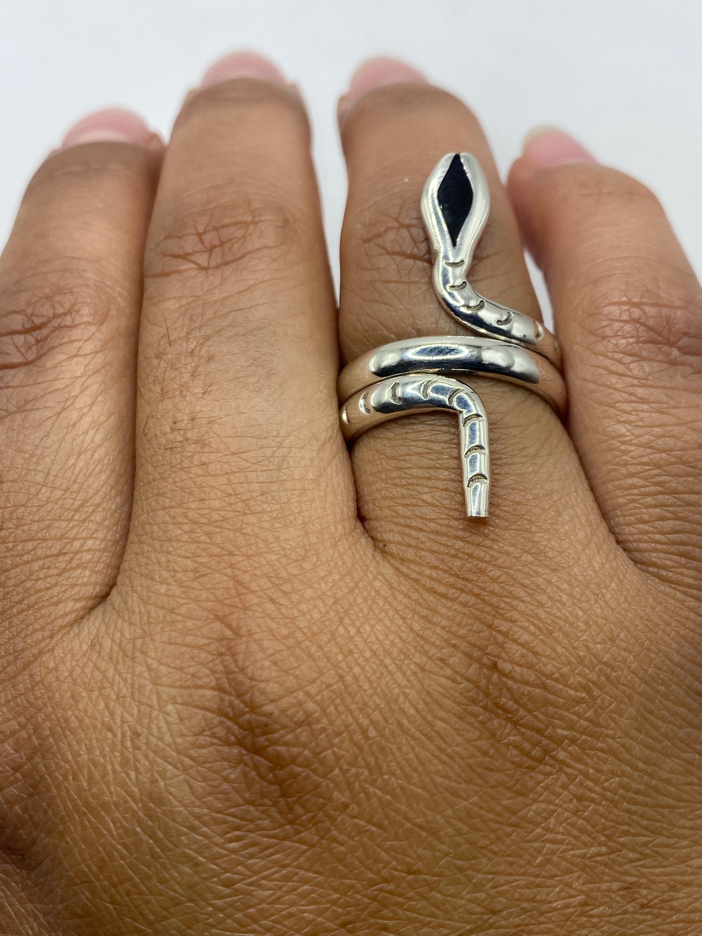 Anillo ónix negro en mano femenina mostrando el diseño serpiente envolvente