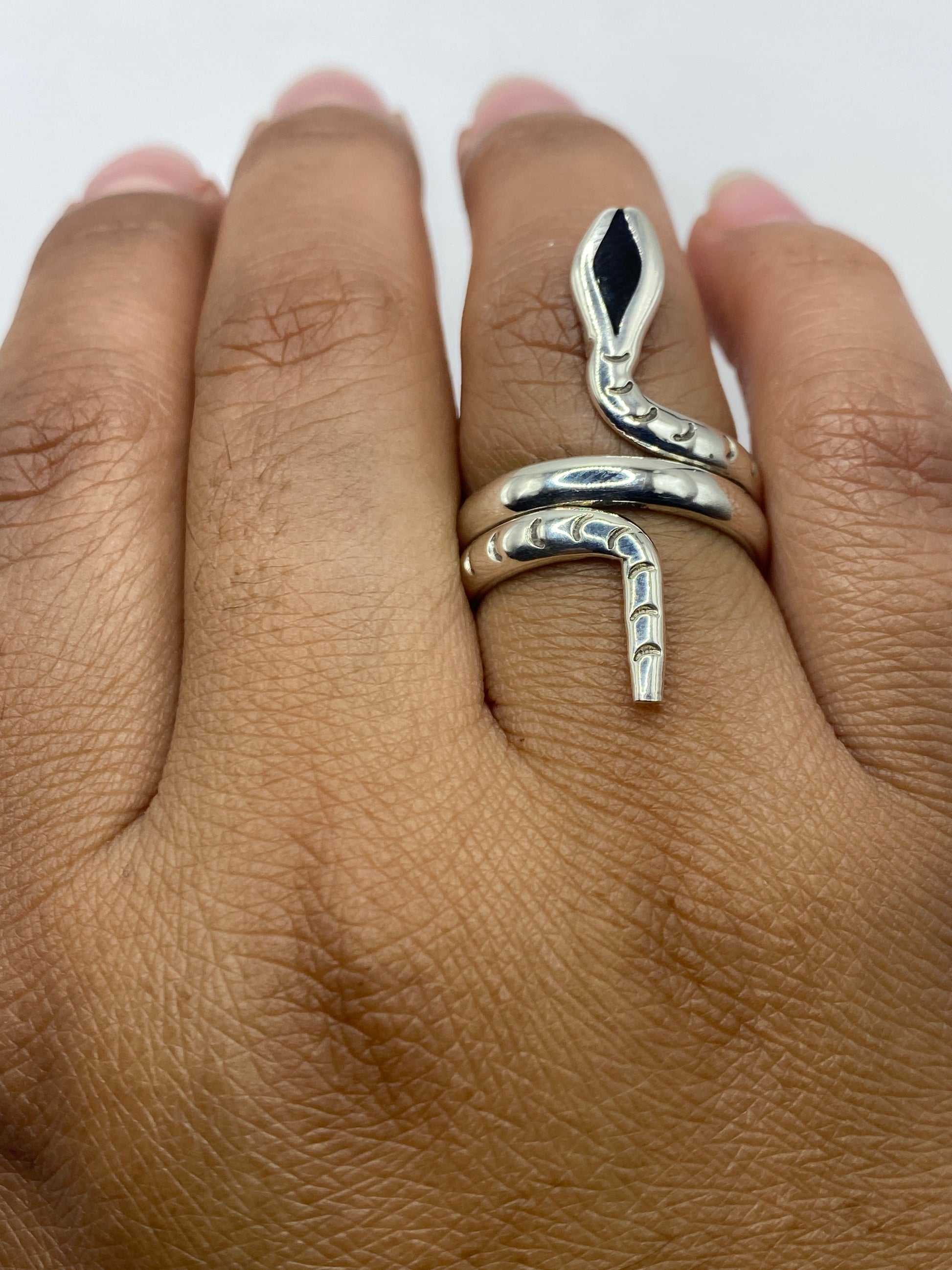 Anillo ónix negro en mano femenina mostrando el diseño serpiente envolvente
