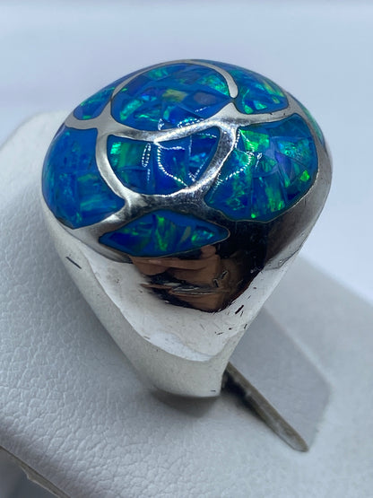 Anillo de plata ópalo de fuego puesto en la mano de una mujer, viéndose el juego de colores