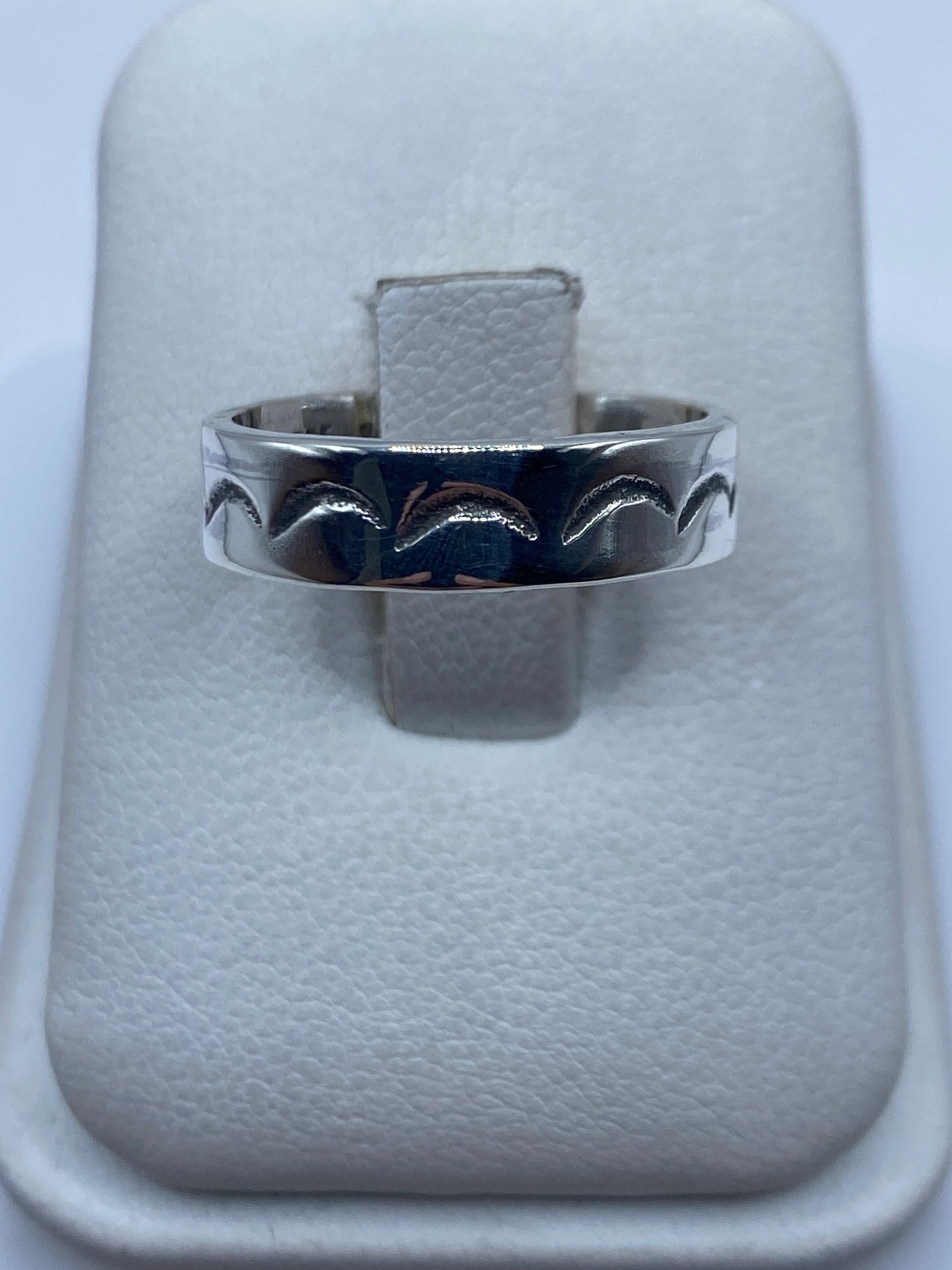 Anillo de plata con ondas grabadas simétricas en la mano