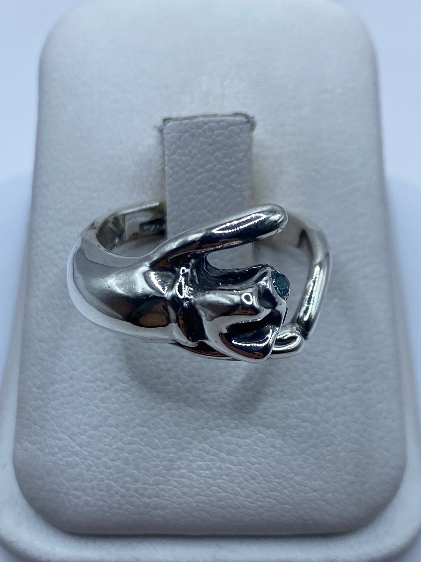 Anillo de plata con mano escultural engastando circonia azul, visto en la mano de una mujer