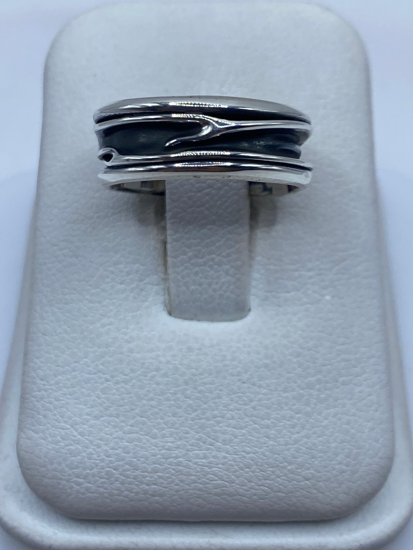 Anillo de plata con bandas superpuestas en los dedos de una persona