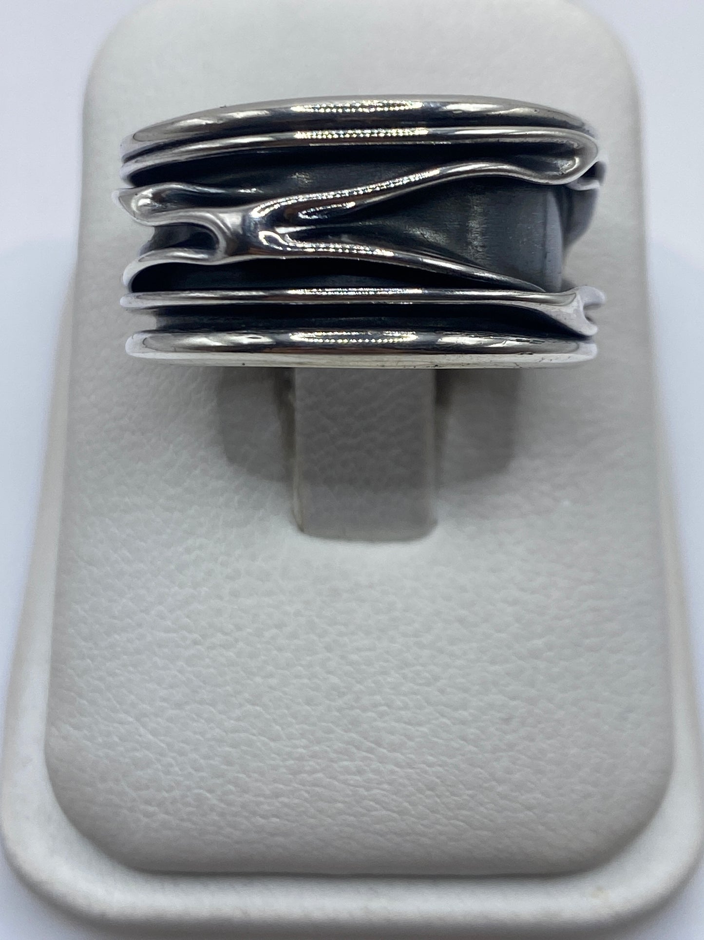 Anillo de plata con bandas superpuestas en posición horizontal sobre fondo blanco