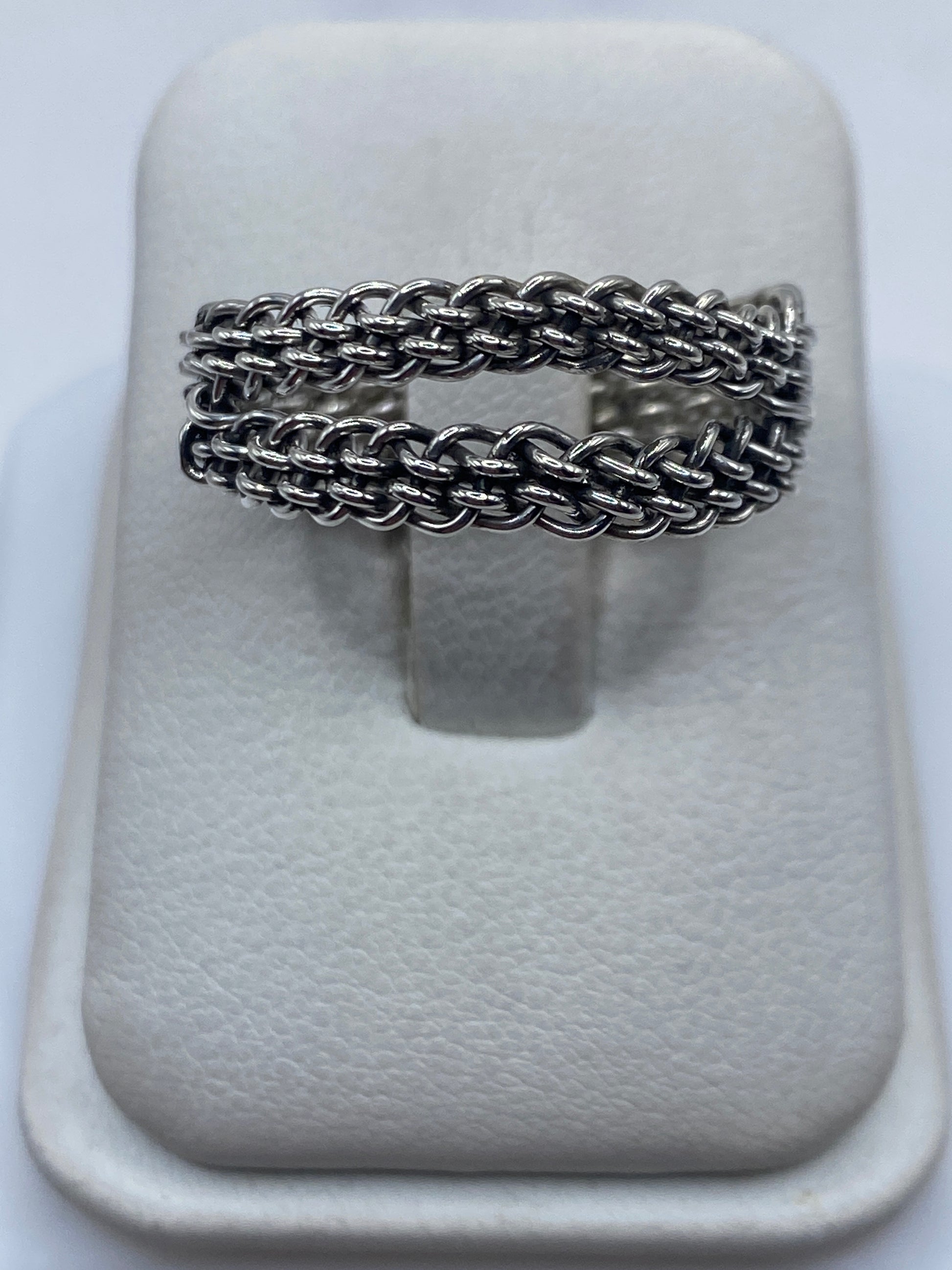 Anillo de plata tejido trenzado sobre fondo blanco, vista frontal