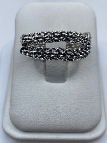 Anillo de plata tejido trenzado sobre fondo blanco, vista frontal