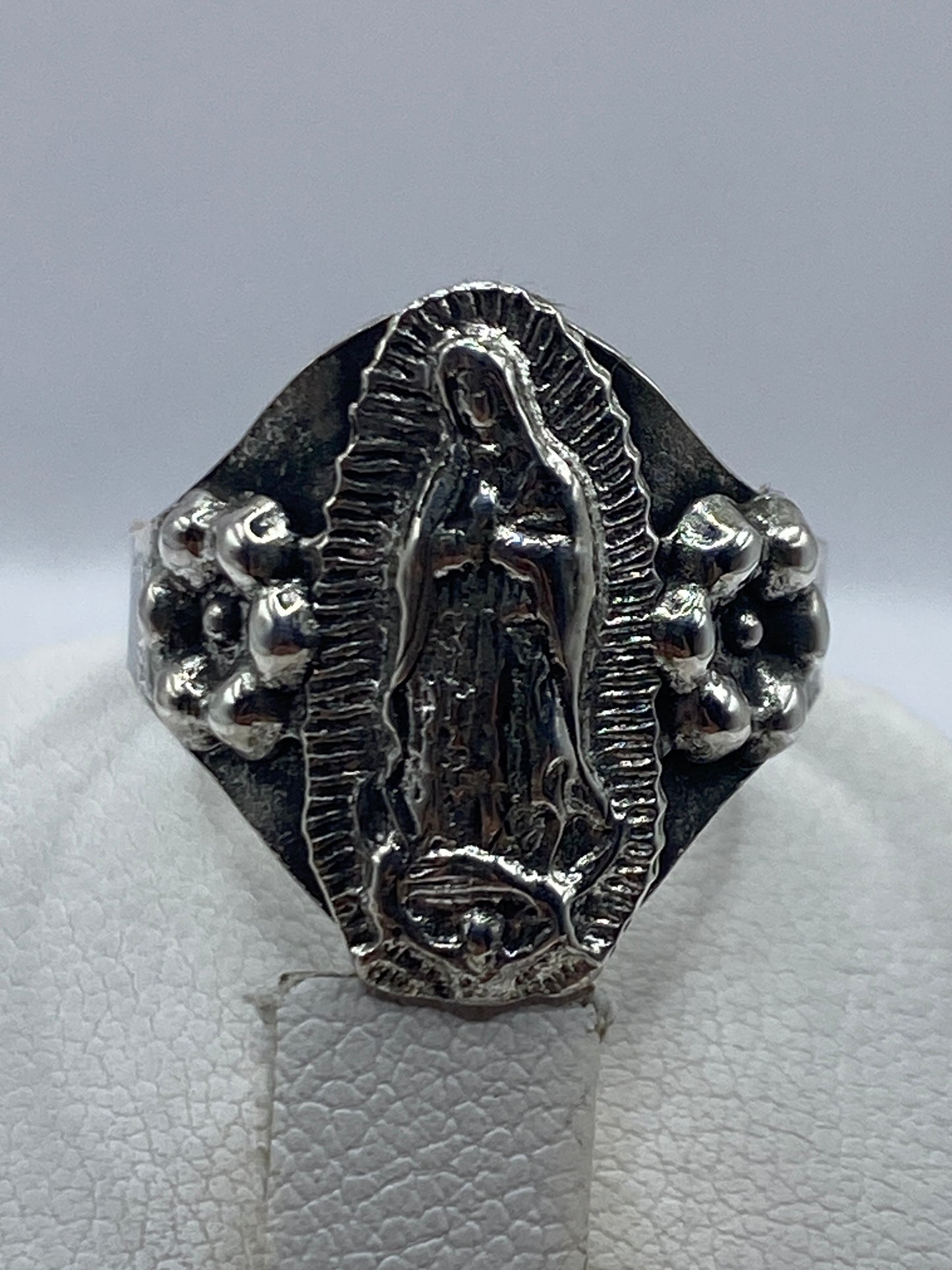 Anillo religioso puesto en dedo, mostrando el relieve del tallado
