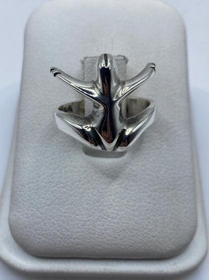 Anillo de plata escultural alas abiertas vista frontal en soporte blanco