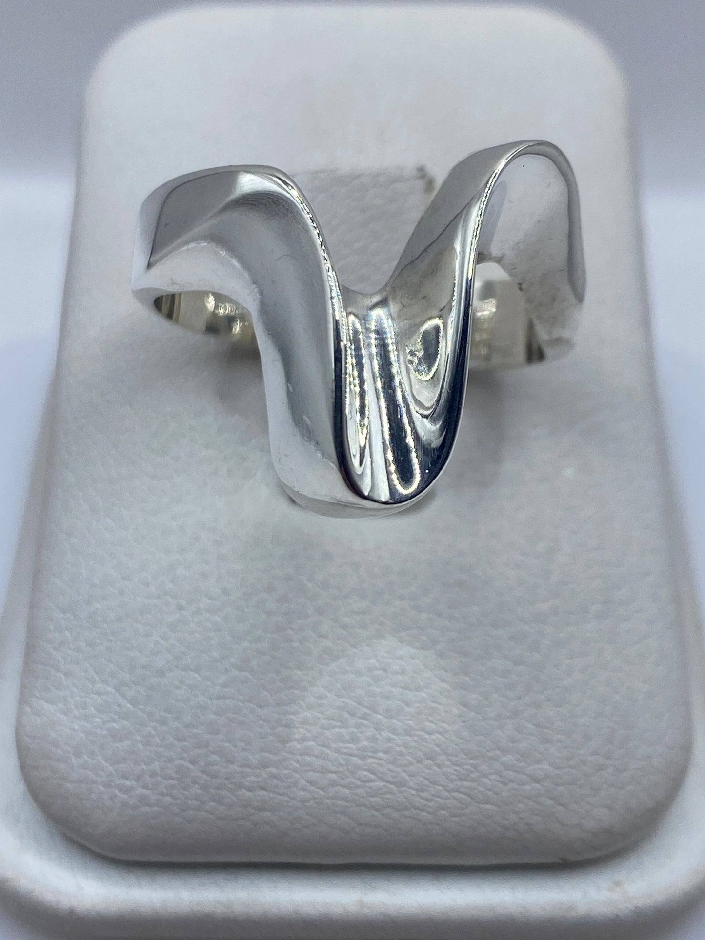 Anillo minimalista de plata .925 con acabado pulido espejo, vista frontal en estuche blanco