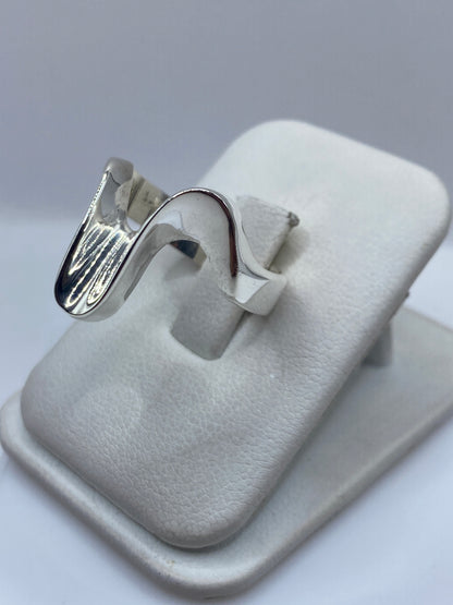 Anillo contemporáneo de plata maciza en la mano, mostrando el diseño ondulante y el brillo del pulido