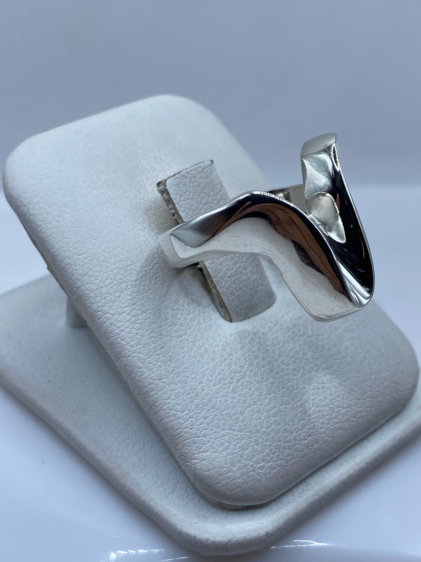 Detalle lateral del anillo solitario mostrando el pulido espejo y la forma ondulante