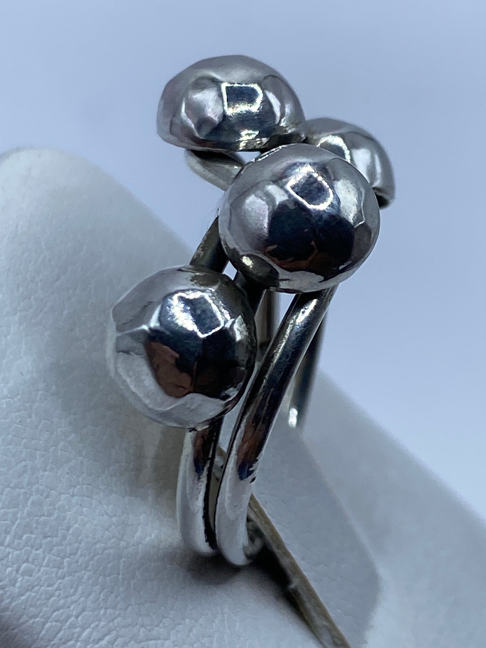 Detalle del anillo en mano femenina mostrando el acabado espejo de las esferas
