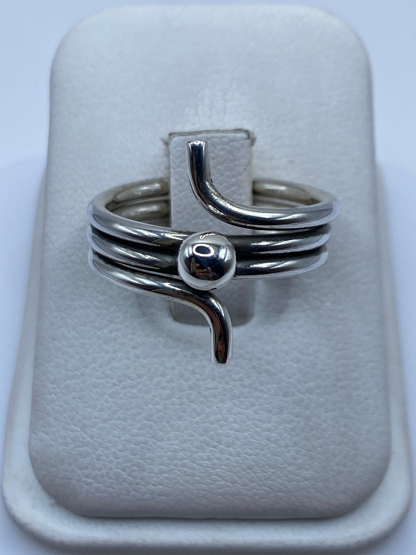 Anillo de plata giratorio con bandas pulidas, posado sobre estuche blanco