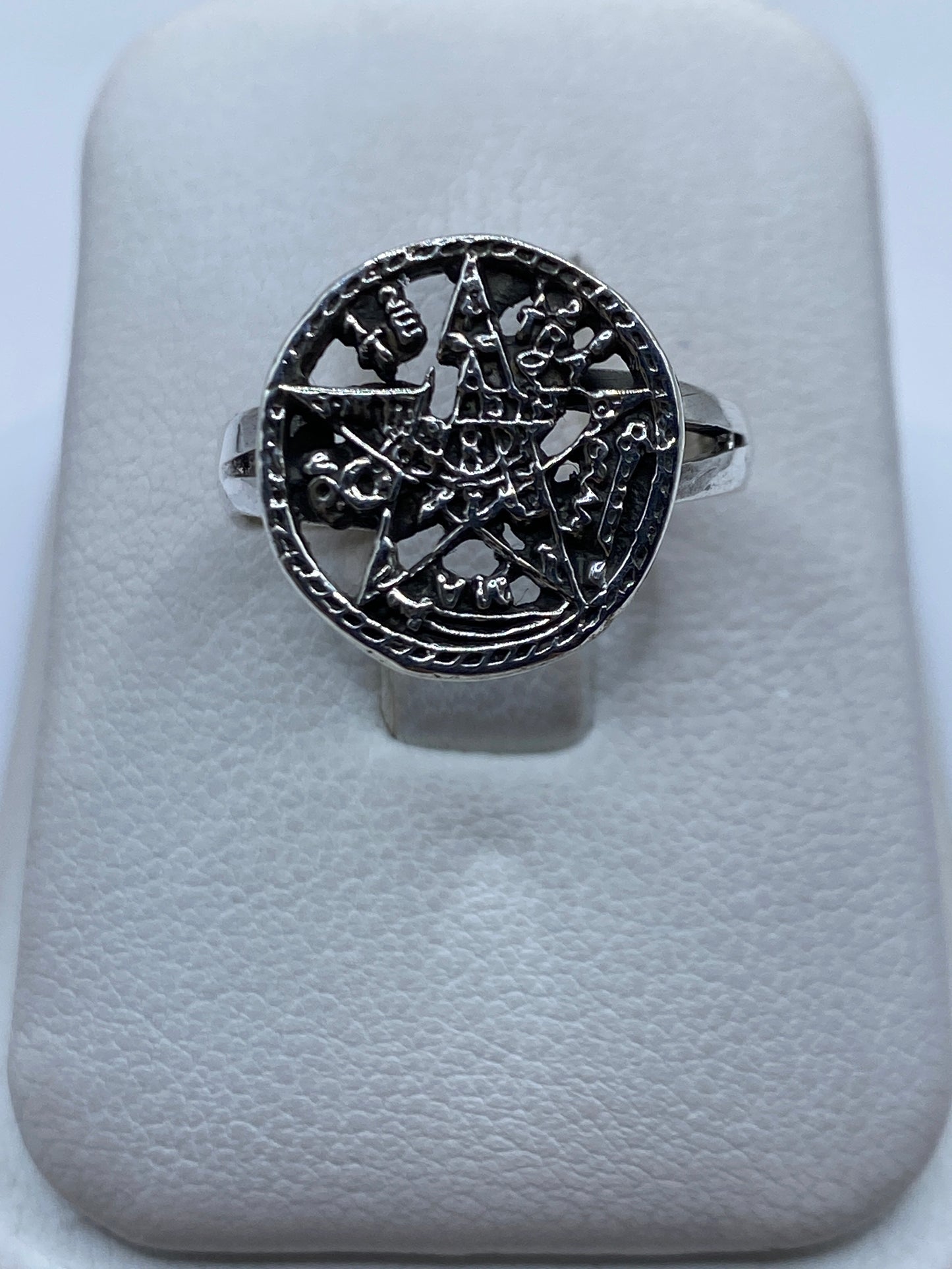 Anillo de plata con símbolo prehispánico tallado, vista frontal sobre anillo de presentación blanco