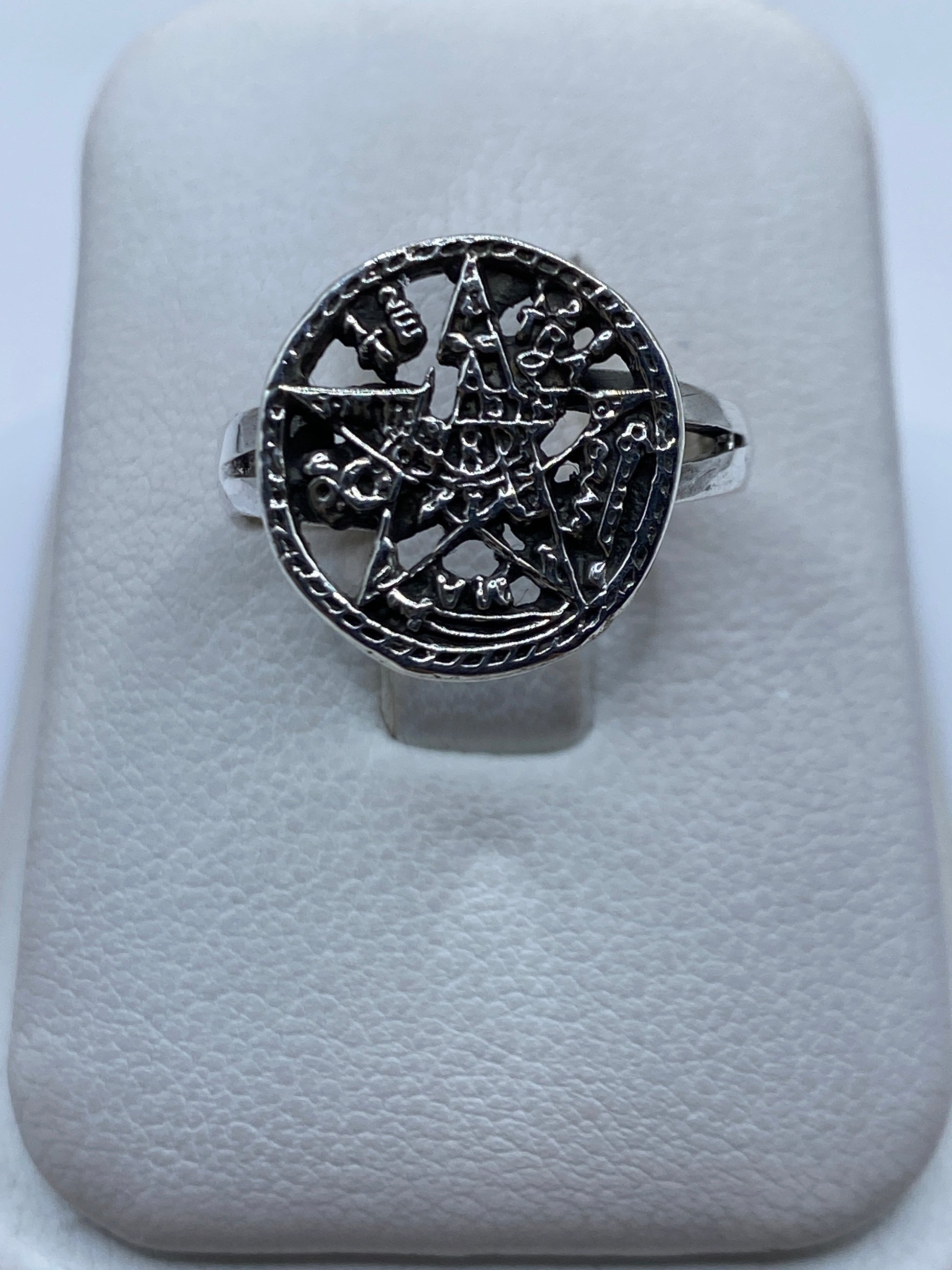 Anillo de plata con símbolo prehispánico tallado, vista frontal sobre anillo de presentación blanco