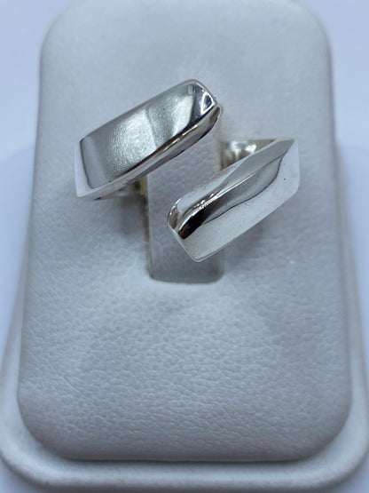 Anillo de plata geométrico ajustable sobre dedo, mostrando diseño moderno pulido