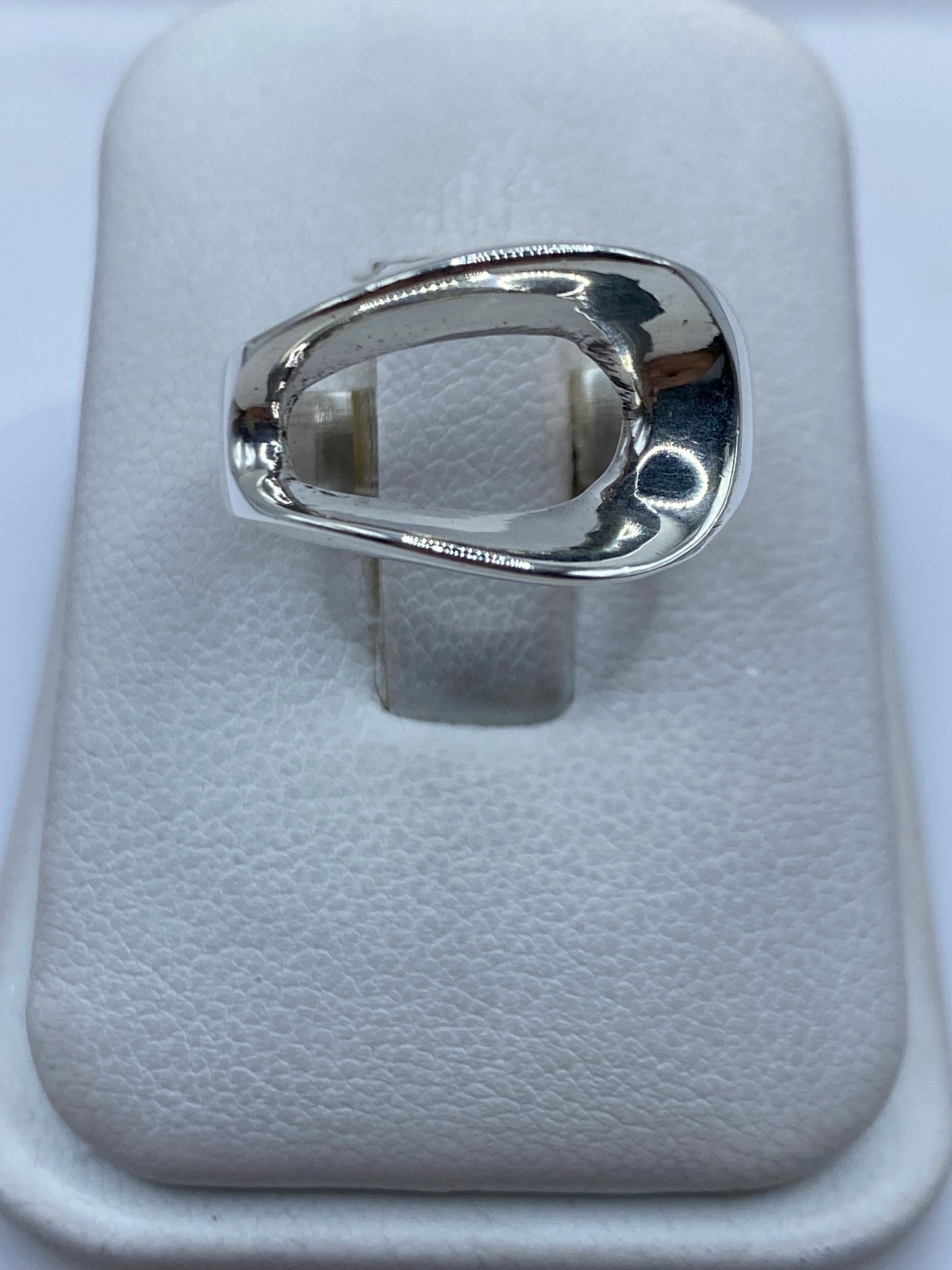 Anillo de plata solitario pulido en la mano de una mujer, mostrando su forma ovalada minimalista