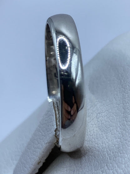 Anillo de banda lisa brillante sobre fondo gris, mostrando el pulido a espejo