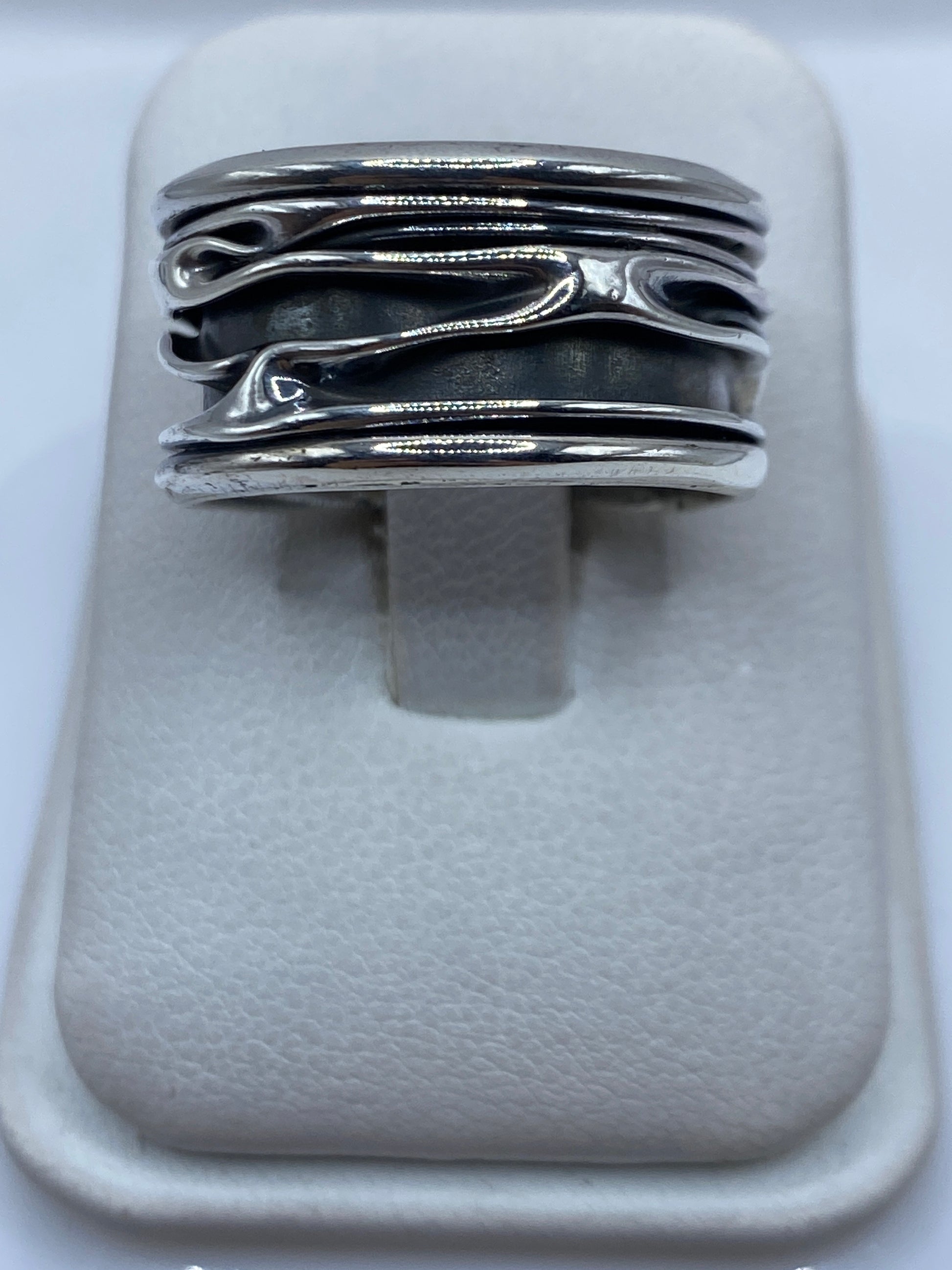 Anillo de plata con bandas fluidas abiertas visto desde arriba en estuche blanco