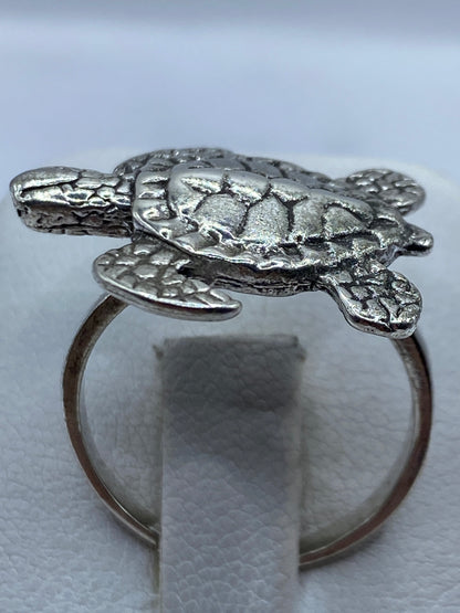 Anillo de plata con tortuga marina en relieve, vista superior sobre fondo blanco