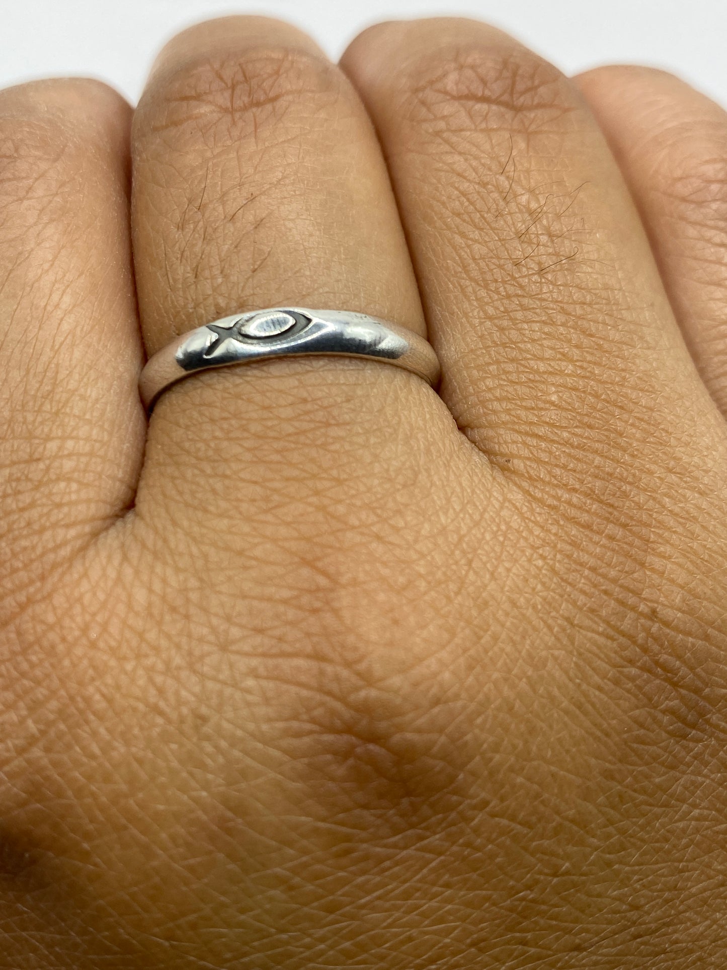 Anillo de plata minimalista sobre fondo blanco mostrando acabado pulido
