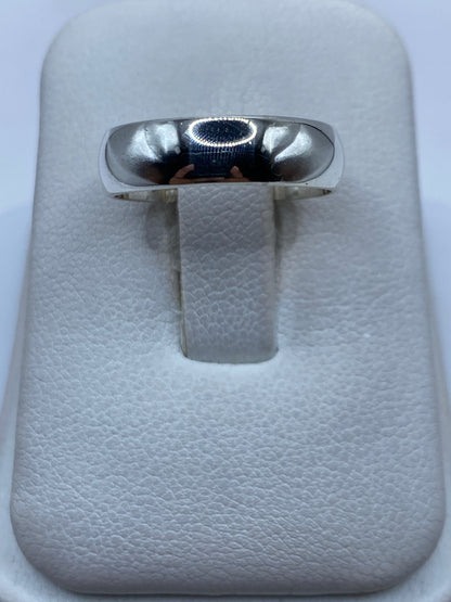 Anillo de plata lisa pulida en una mano, vista frontal de la banda minimalista