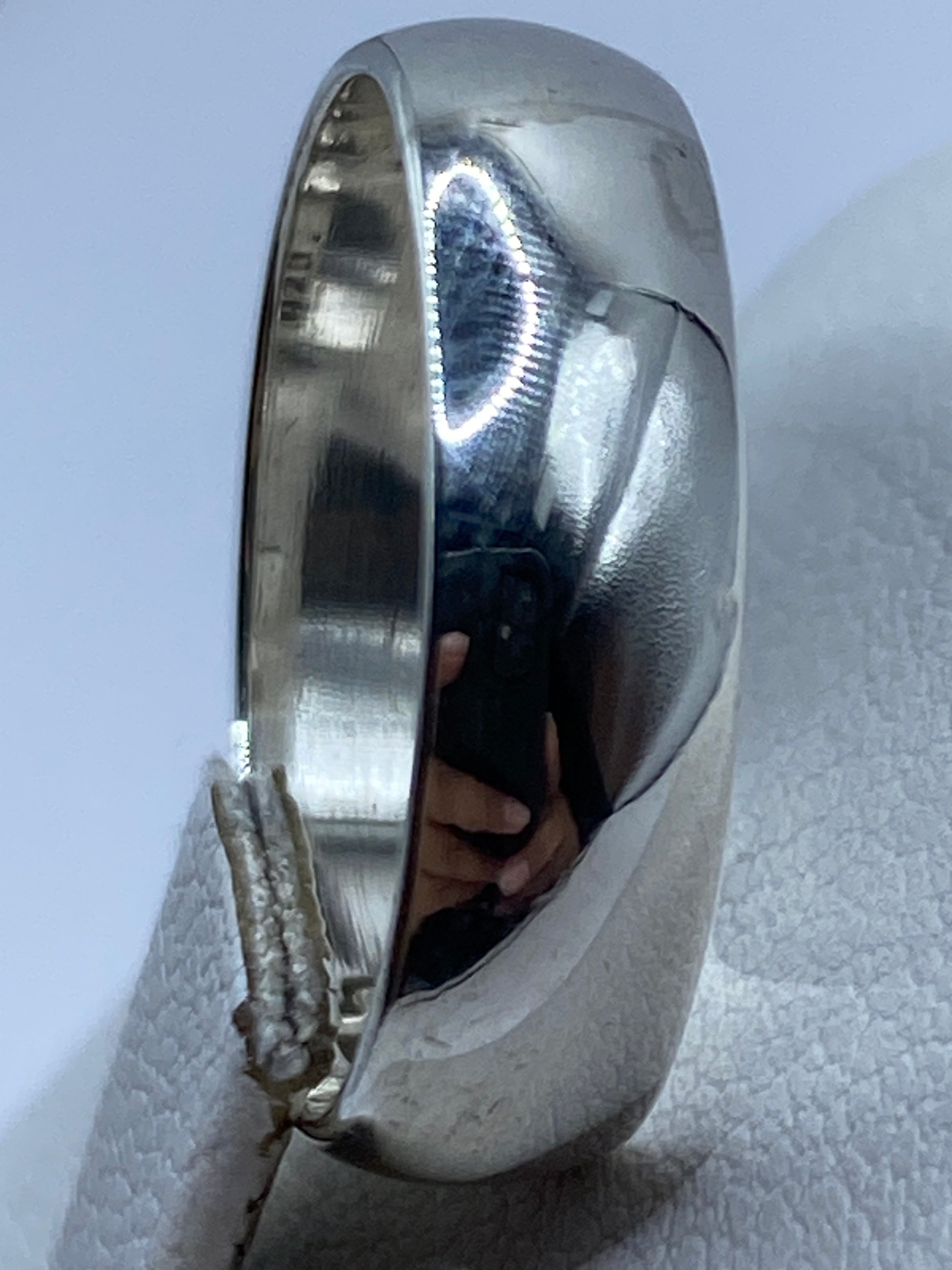 Anillo de plata en perfil sobre fondo gris claro, con sello 925 visible en el interior
