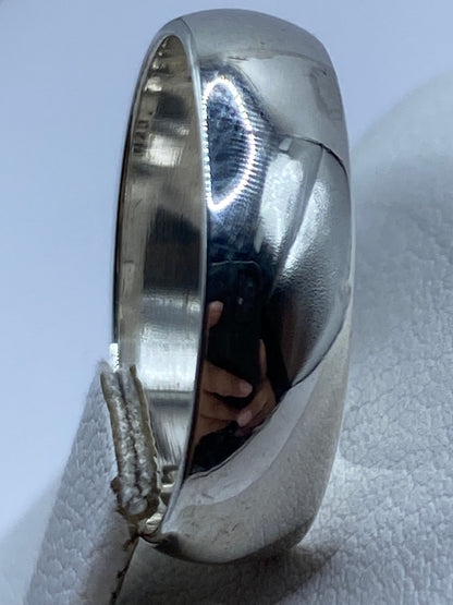 Anillo de plata en perfil sobre fondo gris claro, con sello 925 visible en el interior