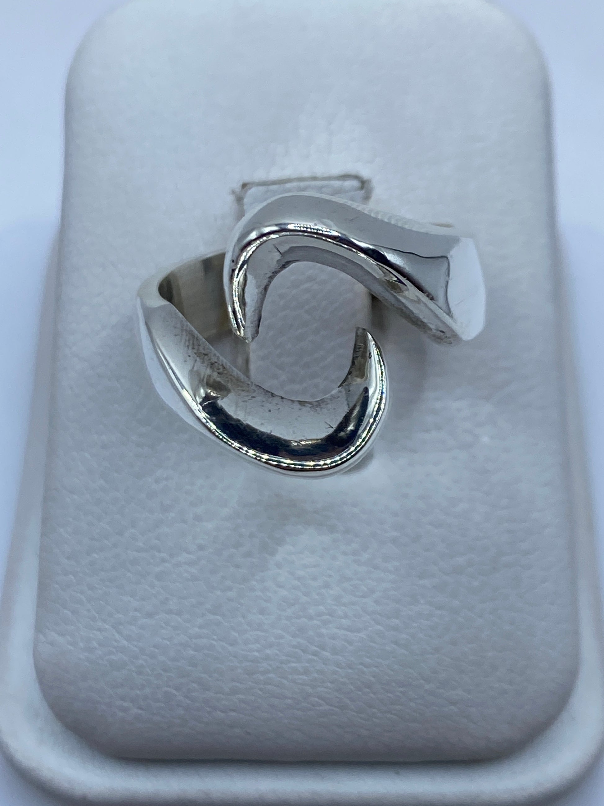Anillo de plata minimalista liso en la mano de una persona, mostrando su acabado pulido