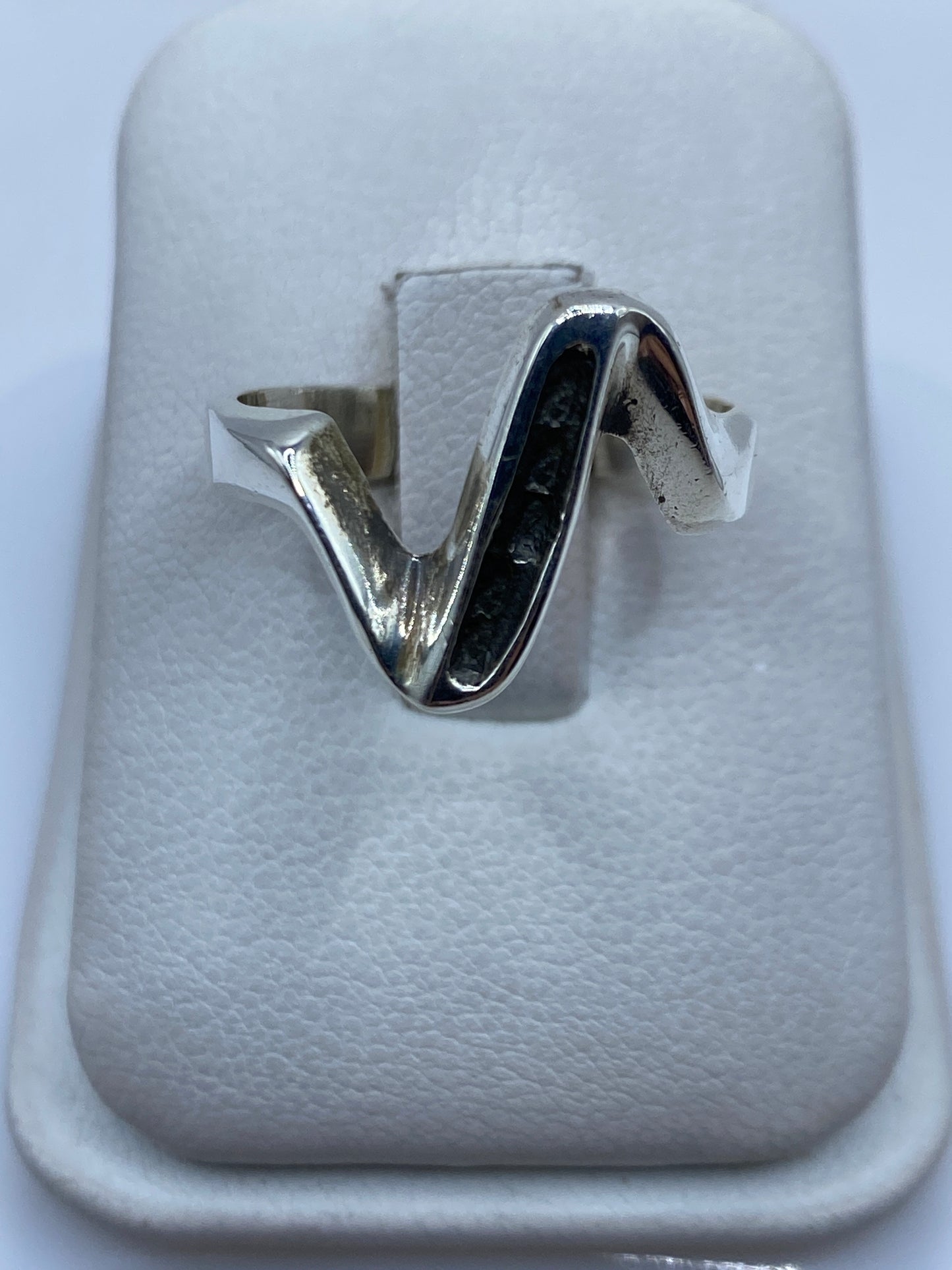 Anillo de plata minimalista en forma de V sobre estuche blanco, vista frontal