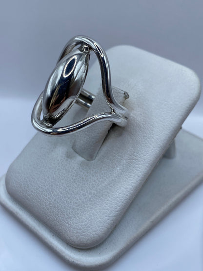 Anillo de plata ovalado puesto en dedo, mostrando pulido brillante y proporciones elegantes