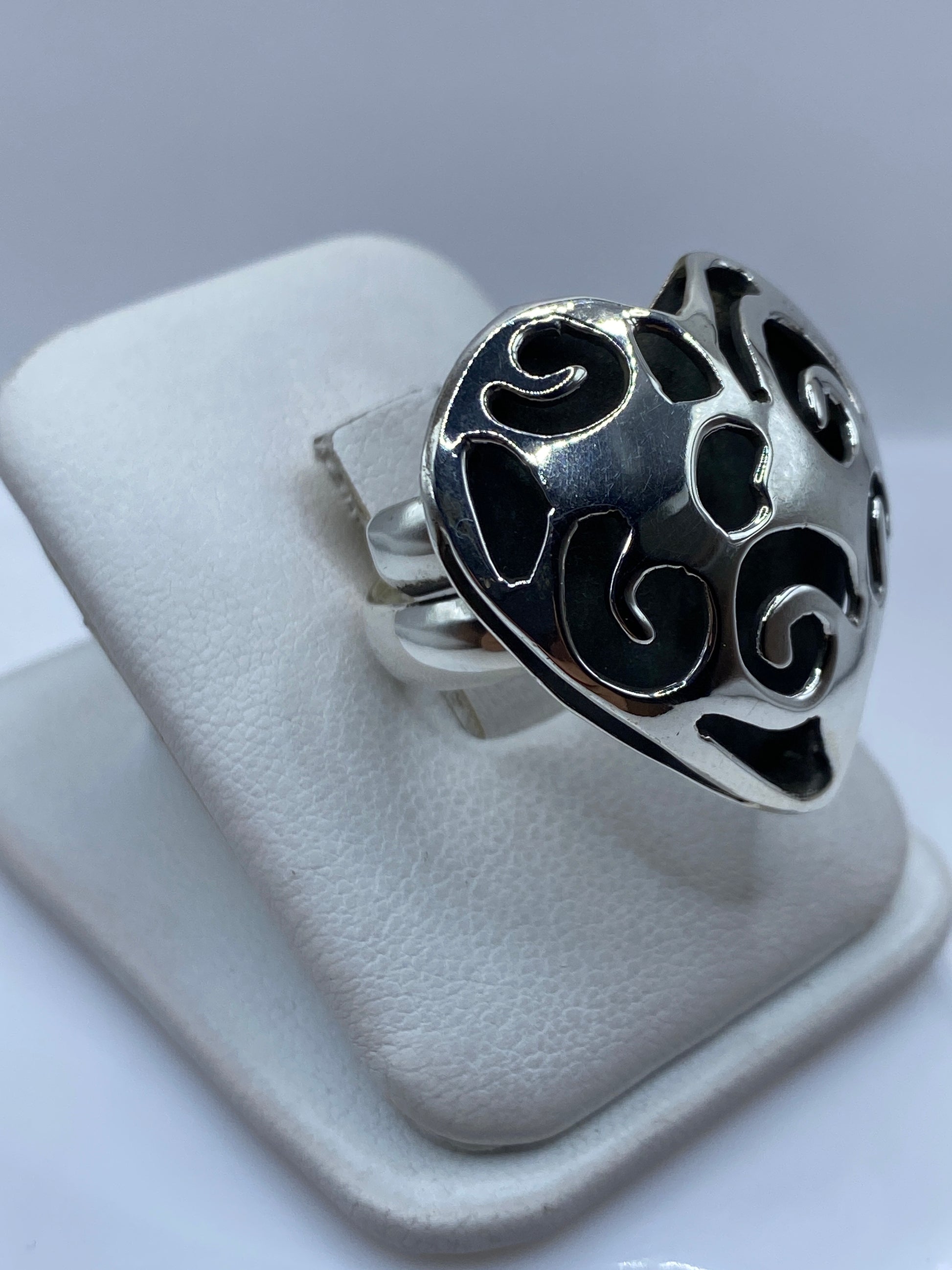 Vista frontal del anillo ajustable corazón calado sobre dedo de mujer