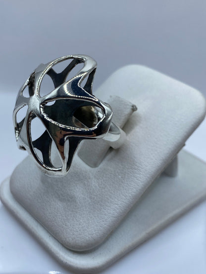Anillo floral en plata pura llevado en la mano, mostrando volumen y contraste de brillos