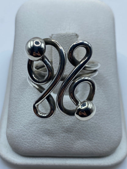 Anillo de plata calado con esferas en bucles geométricos en la mano de una mujer