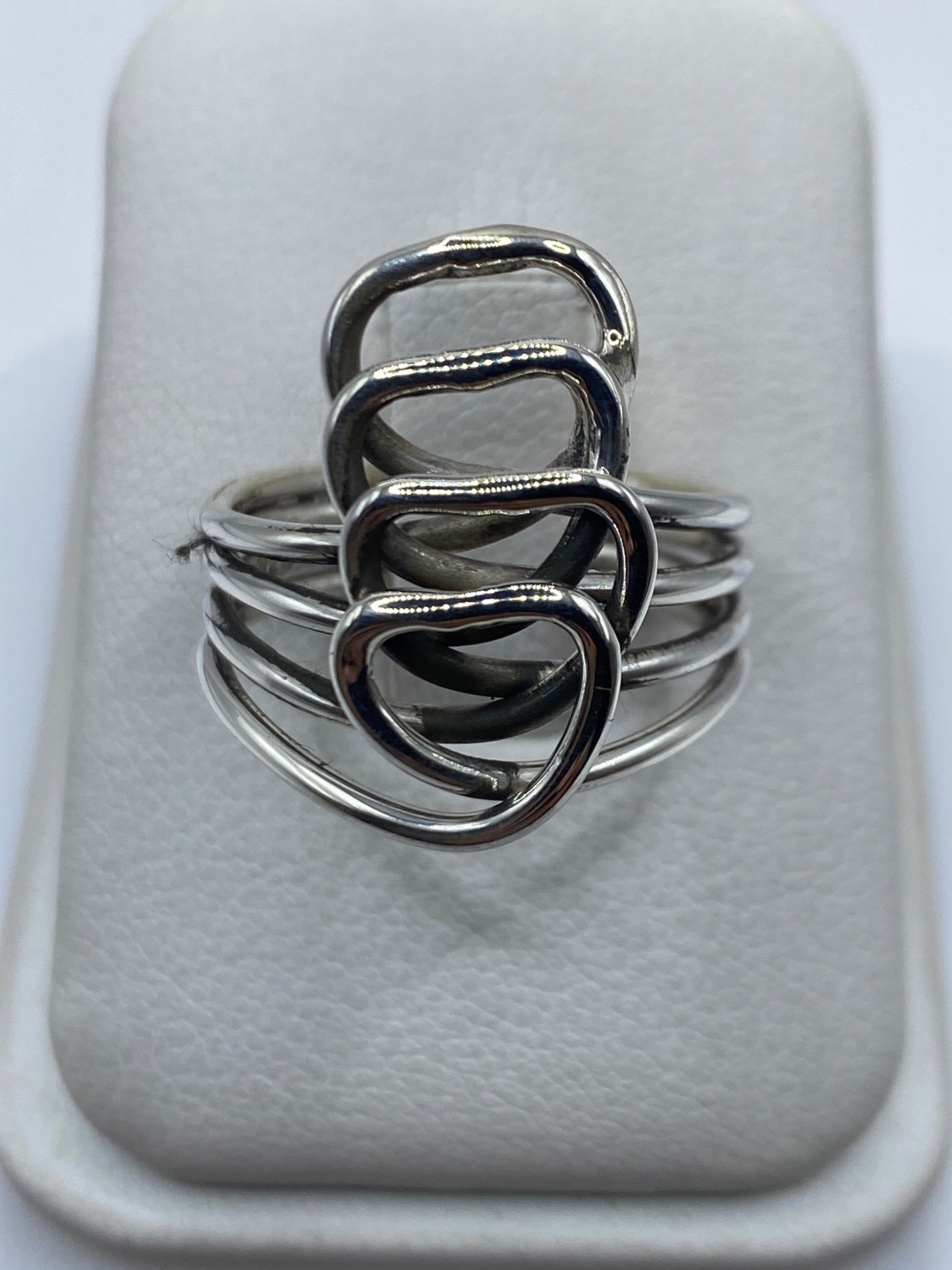 Anillo de plata calado con cuatro corazones entrelazados en mano de mujer