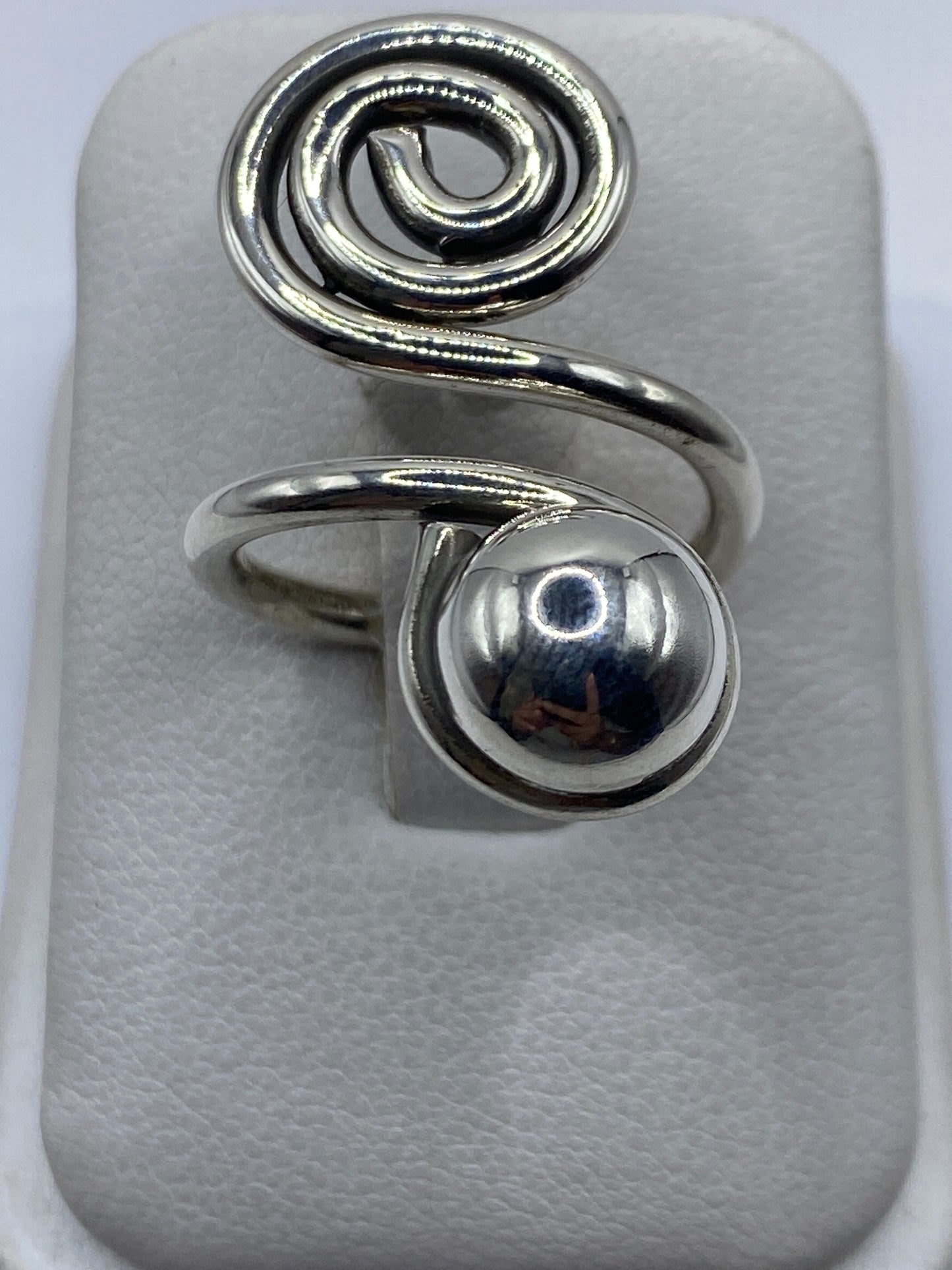 Anillo de plata calado ajustable con diseño en espiral en la mano de una mujer